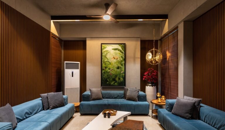 Modern living room with blue sofas, wooden walls, ceiling fan, and vertical garden.
