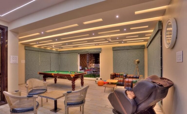 Modern game room with pool table, massage chair, and stylish ceiling lighting.