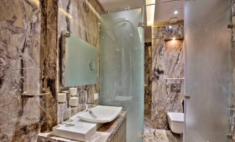Modern bathroom with marble walls, glass shower, and white basin.