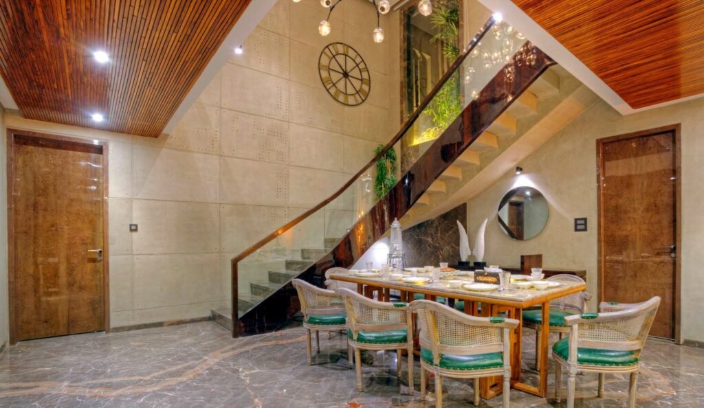 Elegant dining room designed by luxury interior designers in Gurgaon, featuring a wooden table set, marble flooring, and a modern staircase.