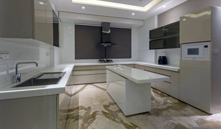 Modern kitchen interior with beige cabinets, a central island, and built-in appliances.