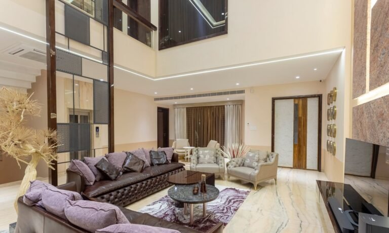 Modern living room with leather sofa, armchairs, marble floor, and high ceiling.