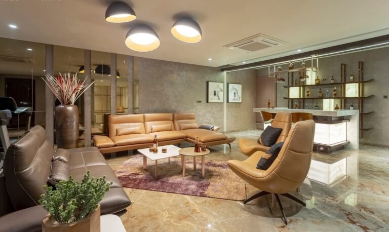 Modern living room with tan leather furniture, pendant lights, and a marble bar area.