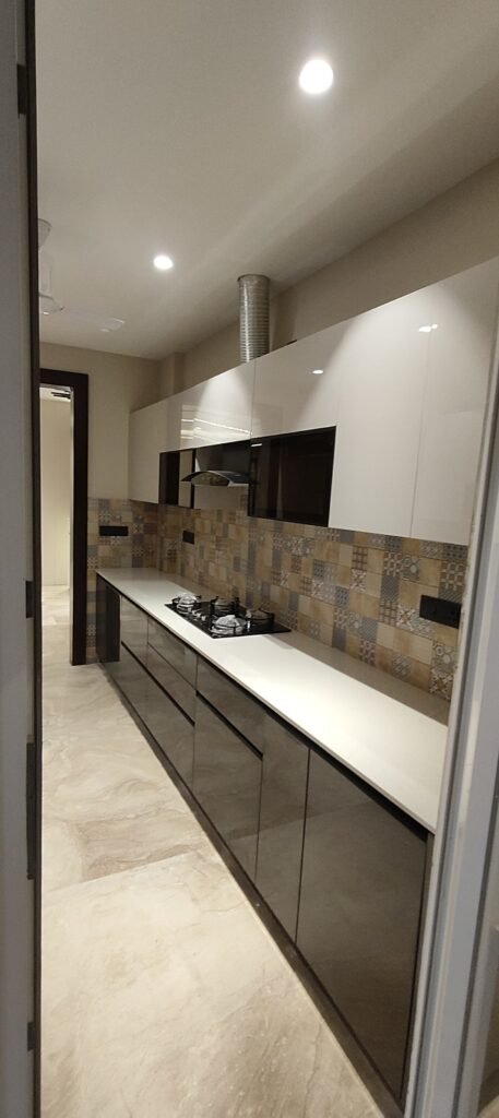 Modern parallel kitchen with glossy cabinets, quartz countertops, patterned backsplash tiles, ceiling fan, and glass door leading to utility area.