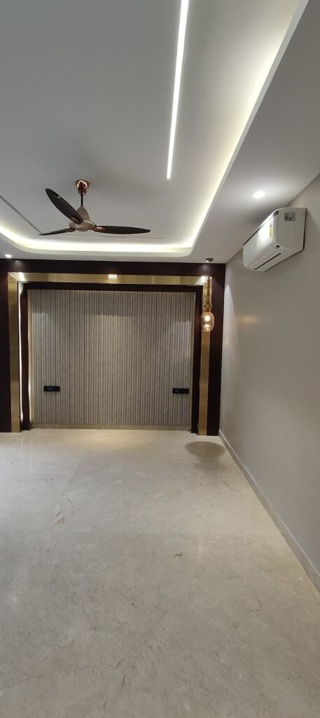 Minimalist modern room with ceiling fan, air conditioner, LED false ceiling lighting, and feature wall with wooden paneling and vertical grooves.