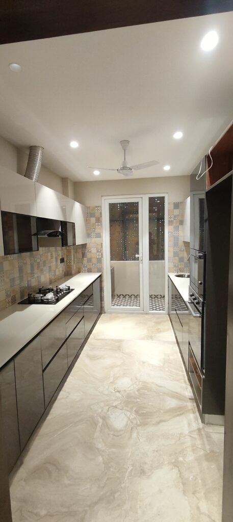 Modern parallel kitchen with glossy cabinets, quartz countertops, patterned backsplash tiles, ceiling fan, and glass door leading to utility area. Modern parallel kitchen with glossy cabinets, quartz countertops, patterned backsplash tiles, ceiling fan, and glass door leading to utility area.